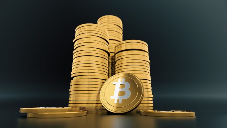 una moneda bitcoin y de fondo tres montones apilados