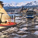Ilustración satírica de un monopatín iluminado junto a una calle con baches en Ushuaia