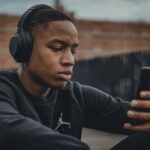 Persona con auriculares escuchando contenido de audio desde un dispositivo móvil